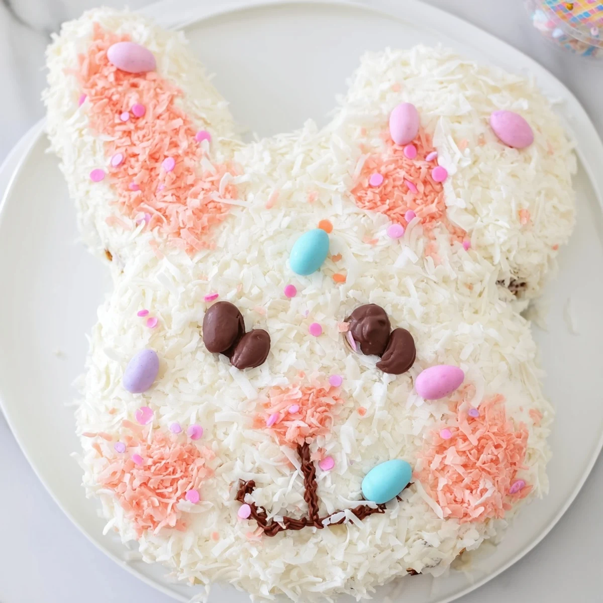Vibrant Spring Bunny Carrot Cake decorated with coconut fur and marshmallow tail, ready to eat.
