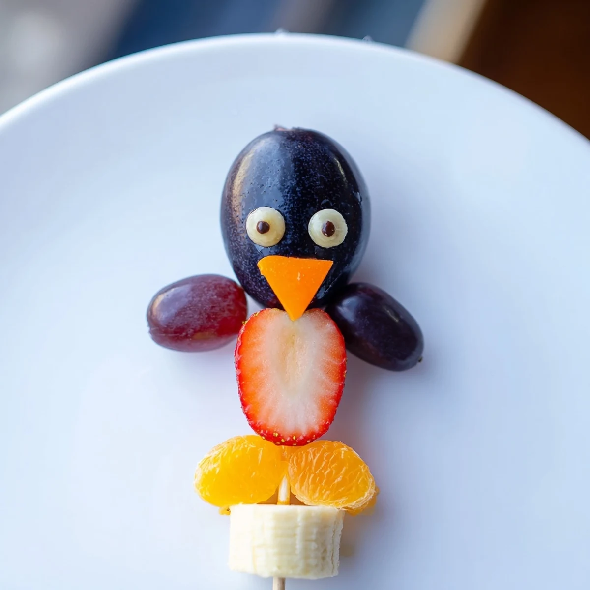 A playful Penguin Fruit Skewer Army featuring strawberries, grapes, and mandarin orange segments; a fun snack.
