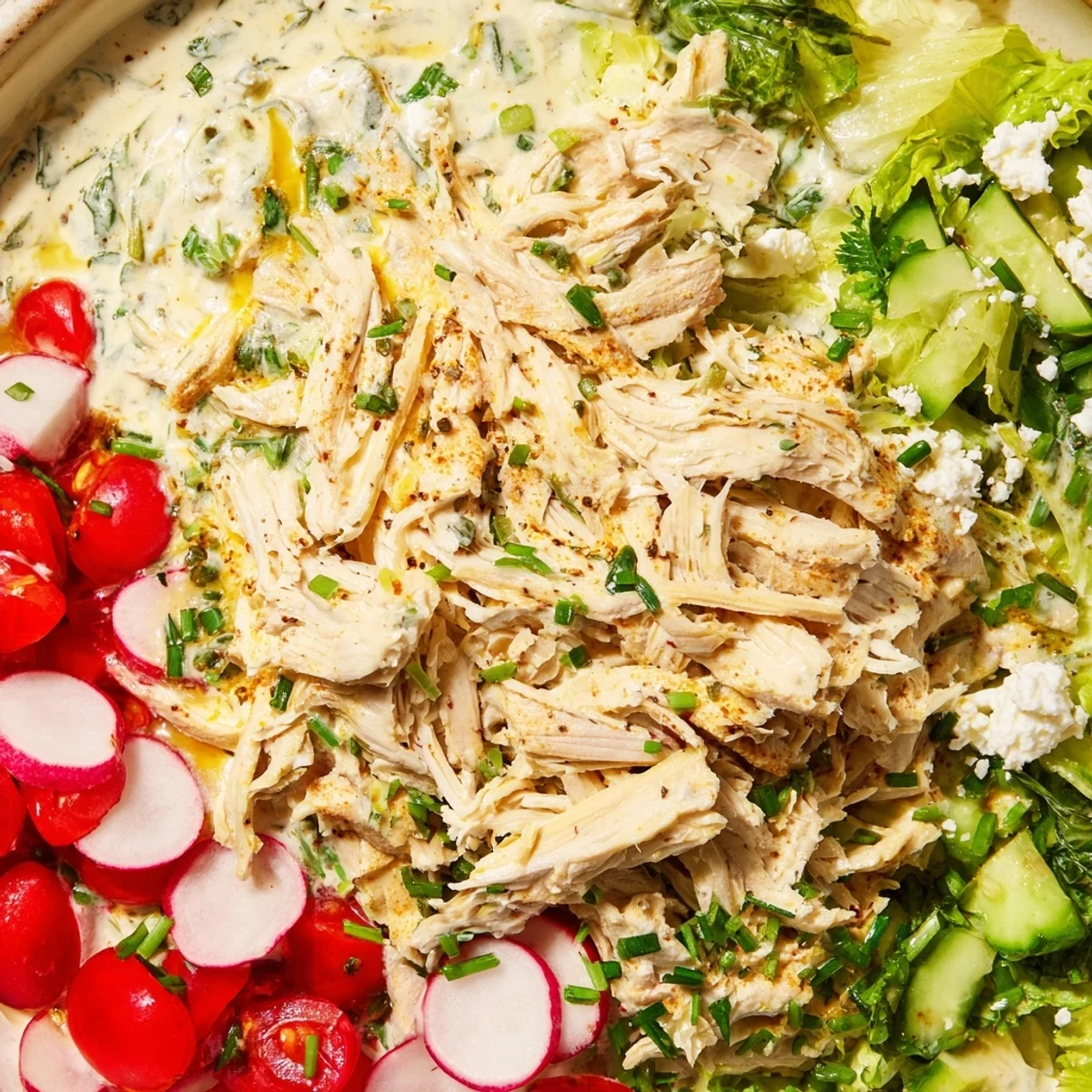 Creamy Green Goddess Chicken Nacho Dip, topped with warm shredded chicken and colorful fresh vegetables.