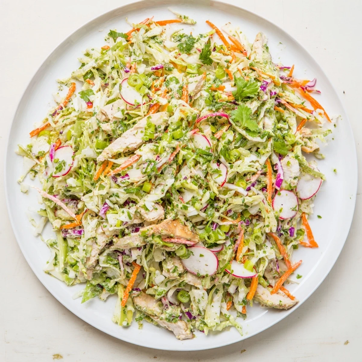 Green Goddess Cabbage Slaw topped with sliced grilled chicken, a flavorful, healthy meal.