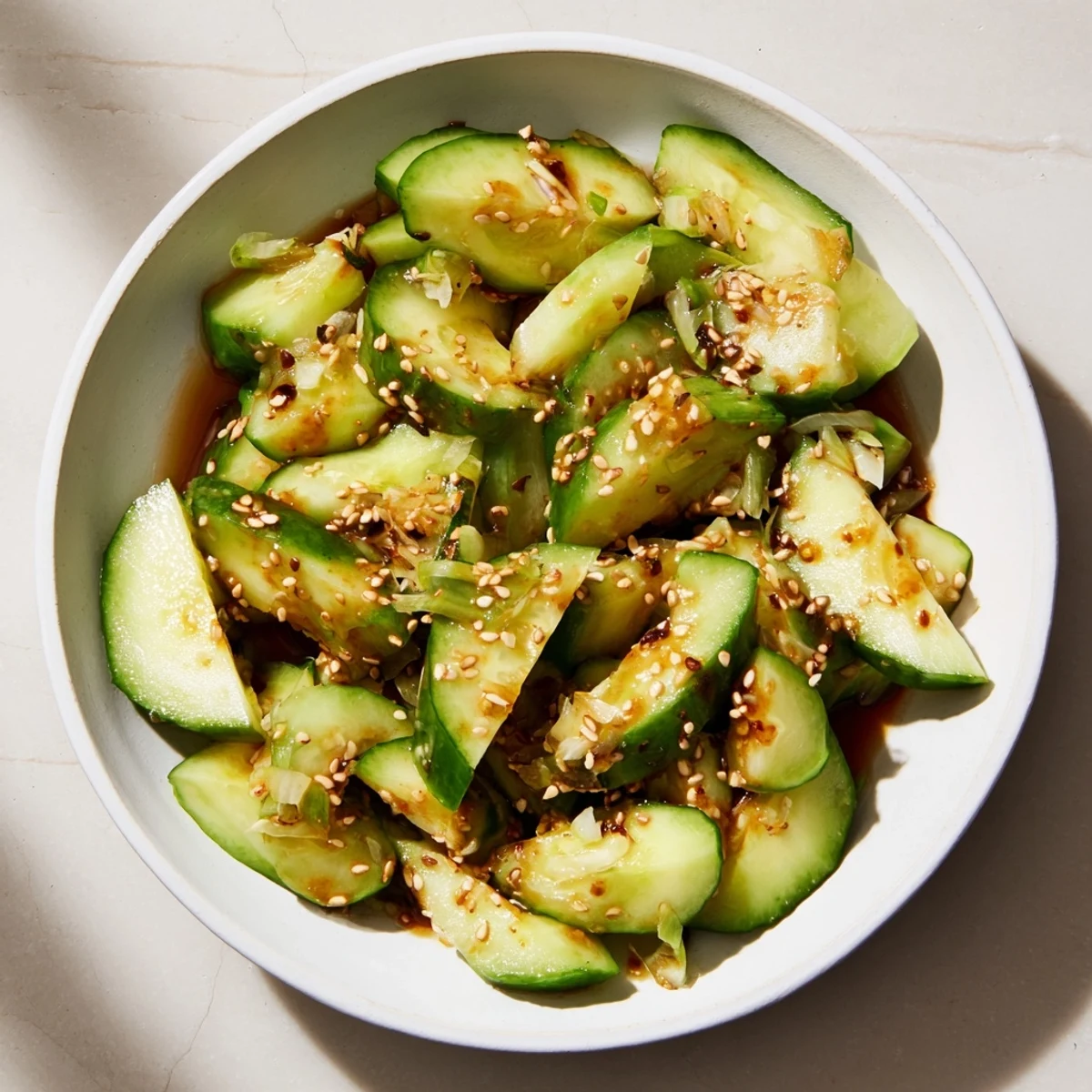 Crisp Cucumber Shaker salad glistening, coated in savory umami sauce and toasted sesame seeds ready to eat.