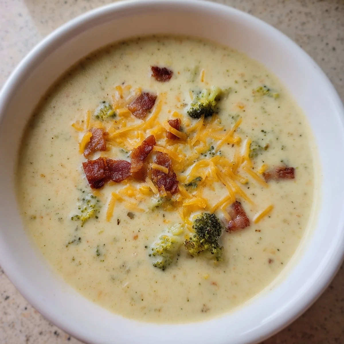 Close-up of a steaming bowl of broccoli cheddar soup, served with toasted, buttery bread slices.