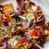 Savory Korean BBQ Nachos, featuring melted cheese and tender beef, are piled high on a crispy chip base.