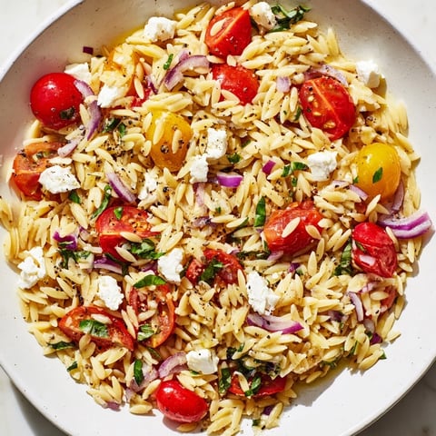 A beautiful bowl of Tomato Feta Orzo pasta salad, bursting with fresh Mediterranean flavors.
