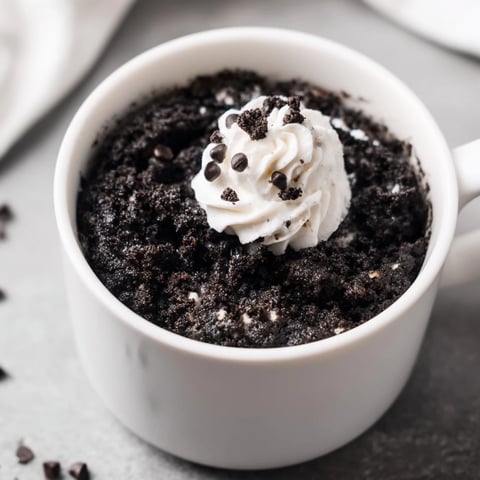 Steaming hot Oreo mug cake, a quick chocolate dessert with melty cookie pieces.