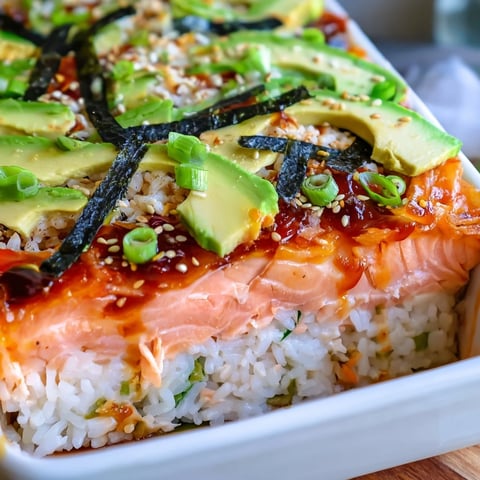 Warm, layered Sushi Bake casserole, creamy salmon and avocado with crispy nori for serving.
