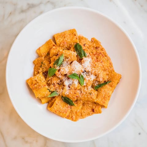 A close-up of creamy roasted red pepper Santa hat pasta illustrates the creamy textures and festive presentation.