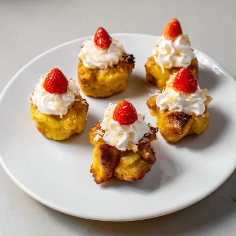 Warm, buttery Santa Hat Bread Pudding Bites served with fresh whipped cream and juicy strawberries.
