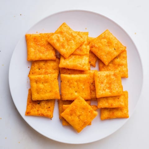 Homemade Crispy Cheeto Cheese Crackers piled high on a serving platter next to a movie night bowl.