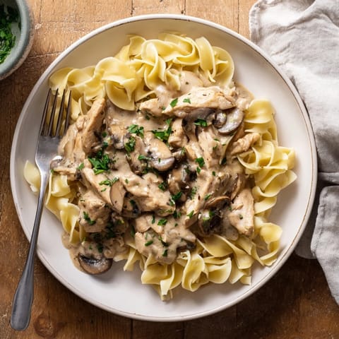 A rustic skillet of Chicken and Mushroom Stroganoff features savory browned mushrooms and herbs, served hot as a hearty main dish.
