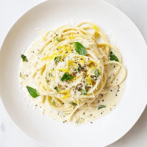 A close-up of fork-twisted Lemon Ricotta Pasta with bright yellow lemon zest and melted cheese coating each strand.  