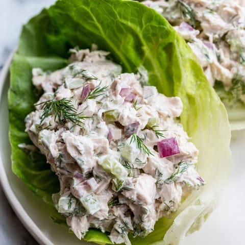 Tangy dill pickle chicken salad with red onion and celery piled high inside refreshing, cool lettuce leaves.  