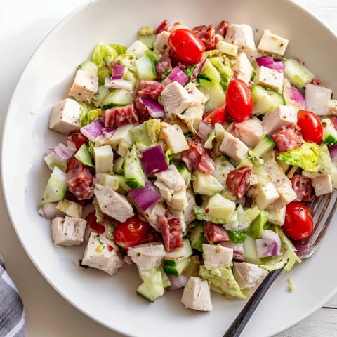 Served in a rustic bowl, the Italian Deli Chopped Chicken Salad features juicy chicken, salty salami, sharp provolone, and crunchy veggies with a zesty dressing.