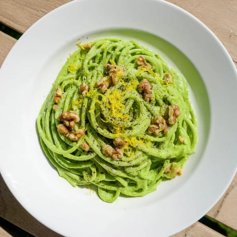 Spoonful of velvety Creamy Spinach Walnut Pasta glistens beside a glass of white wine on a rustic table, perfect for a quick, vegan weeknight meal that comforts and nourishes.