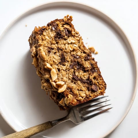 Freshly baked Chocolate Chip Peanut Butter Oatmeal Banana Bread sliced, revealing melty chocolate chips and hearty oats.