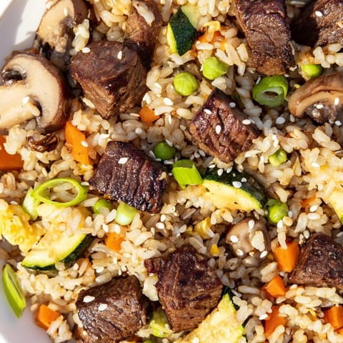 Golden fried rice with tender steak pieces, peas, and carrots, served steaming hot for a delicious Japanese-inspired weeknight dinner.  