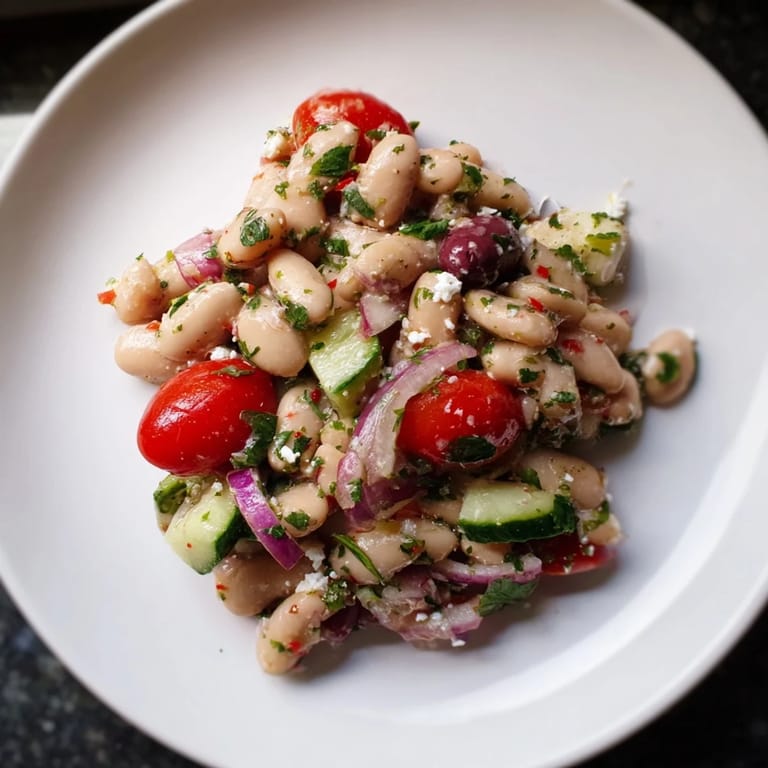 Freshly tossed White Bean Salad, showing plump beans and juicy tomatoes, ready to serve with crusty bread.