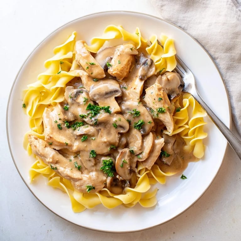 Enjoy rich Chicken and Mushroom Stroganoff with silky sauce and fluffy noodles, garnished with fresh parsley for a classic weeknight meal.