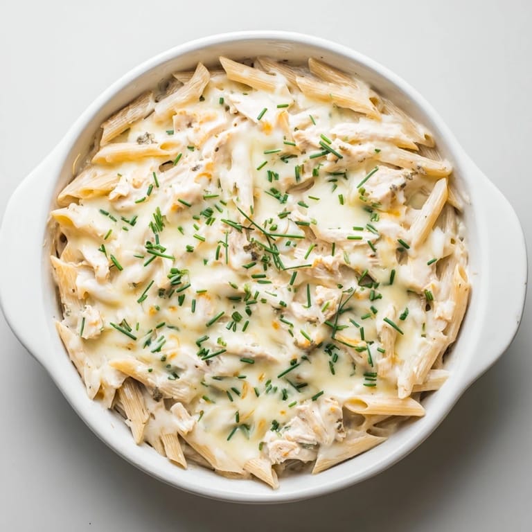 Close-up view of the Chicken Ranch Pasta Bake casserole, highlighting the golden, bubbly mozzarella cheese and creamy ranch sauce coating the pasta.