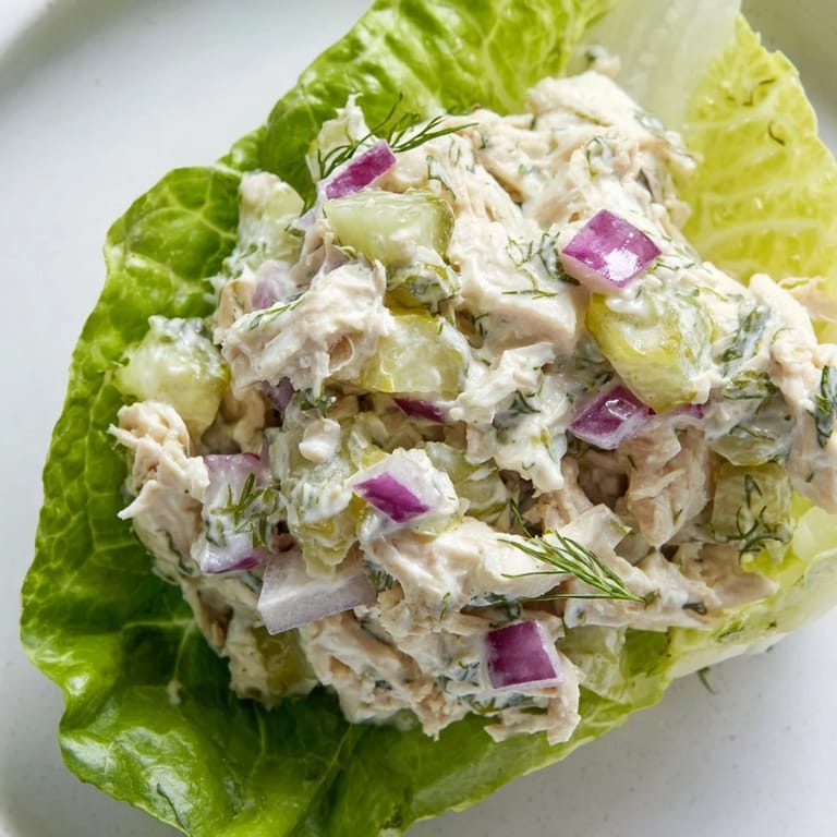 Easy gluten-free dill pickle chicken salad in lettuce cups garnished with fresh dill and a pickle spear.