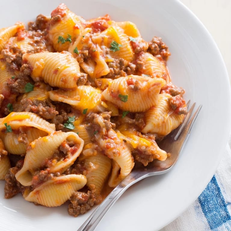 Steaming One Pot Beef and Shells served in a white bowl, showing tender pasta shells coated in rich tomato cream sauce.