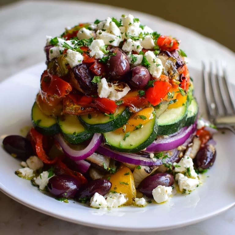 Fresh, zesty lemon-oregano dressing coats this Roasted Greek Salad, served warm with feta and parsley garnish.