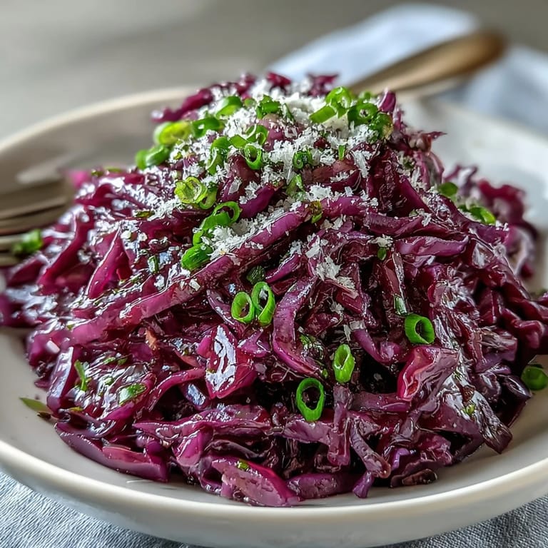 Close-up of crunchy Red Cabbage Coleslaw with Apple and Parmesan, showing glossy dressing and sharp cheese on vivid purple cabbage.