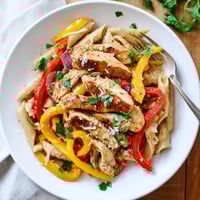 Creamy Cajun Chicken Pasta Lite features al dente penne and juicy chicken strips in a light, spicy sauce garnished with fresh parsley.  