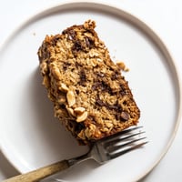Freshly baked Chocolate Chip Peanut Butter Oatmeal Banana Bread sliced, revealing melty chocolate chips and hearty oats.